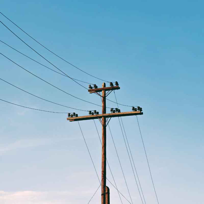 sluzebnosc-przesylu-slupy Drewniany słup niskiego napięcia z liniami energetycznymi biegnącymi nad prywatną działką<br />
